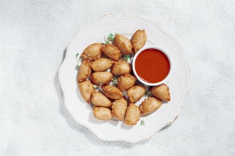 Fried mini chebureks, with sauce, on a decorative plate, hard light, no people