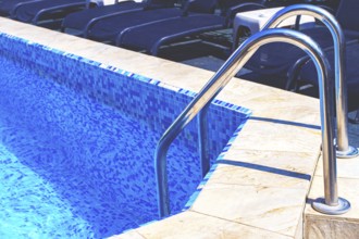 Bright blue swimming pool with ladder under clear sky, perfect for relaxation on a sunny day