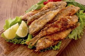 Fried crispy red mullet fish, on a wooden chopping board, with lime, no people