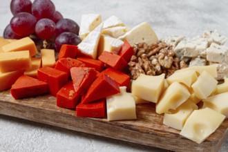 Assorted cheese on a wooden board, with grapes and walnuts, appetizer, no people