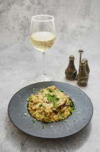A plate of risoni pasta featuring flavorful porcini mushrooms is garnished with fresh herbs