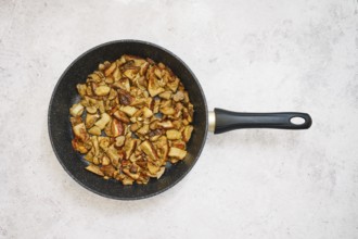 Diced porcini mushrooms are frying in a black pan, creating a savory meal. The cooking process