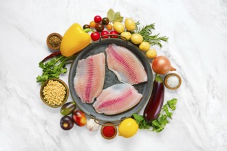 Three raw red seabream fish fillets on a round platter, surrounded by fresh vegetables like