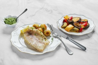 A beautifully arranged meal features tender fish fillet alongside roasted colorful vegetables and