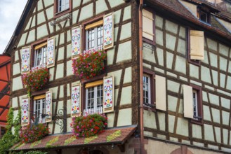 Decorated half-timbered house with ornate windows and flowers in the old town centre of Kaysersberg