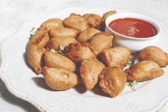 Fried mini chebureks, with sauce, on a decorative plate, hard light, no people