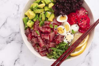Fresh poke bowl, with tuna, avocado, and vegetables, served on a white plate