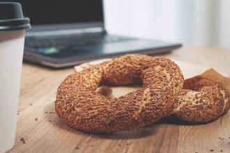 Simits with coffee on a wooden table, with a laptop, in a cozy working environment, snack,