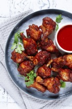 Crispy pieces of fried chicken, on a plate with sauce and herbs, in a modern kitchen environment,