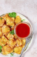 Fried ravioli with parmesan cheese, served with red sauce and garnished with herbs, on a light