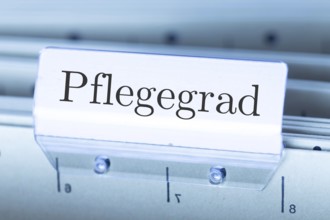 (Photomontage) Sign with the inscription PFLEGEGRAD on a suspension file folder