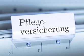 (Photomontage) Sign with the inscription PFLEGEVERSICHERUNG on a suspension file index
