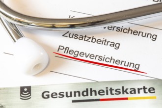 Close-up of the word PFLEGEVERSICHERUNG on a document, plus a medical card and a stethoscope