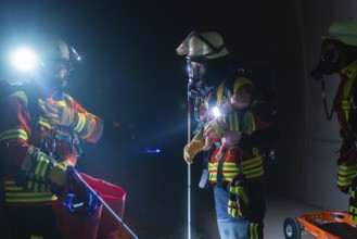 Firefighters in action on rails, equipped with helmets and torches, fire drill in the new