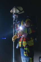 Firefighter with breathing mask and child dummy during a night-time operation, firefighting