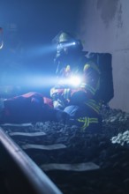 Rescue worker sitting on rails with helmet and breathing mask in dark surroundings, fire brigade