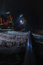 Rescue workers in the tunnel on railway tracks in the dark with blue lights, fire brigade exercise