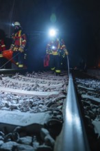 Firefighters on rails, the surroundings illuminated by emergency lighting, firefighting exercise in