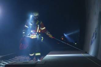 Fireman on a railway platform, at work in the evening with a torch, fire drill in the new