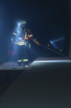 Fireman with glow stick on a railway track, illuminated surroundings, fire drill in the new