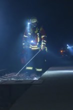 Firefighter examining railway track with lantern in a dark environment, firefighting exercise in