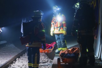 Group of firefighters at night on railway tracks with rescue stretchers, firefighting exercise in