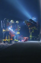 Firefighters working on the tracks at night, illuminated by helmet lamps, firefighting exercise in