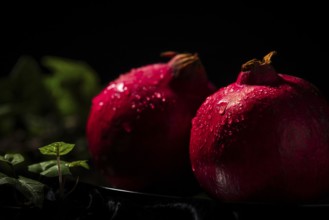 Two pomegranates with drops of water in a dark atmosphere