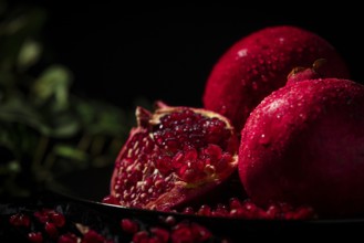 Sliced pomegranate with protruding seeds in a dark atmosphere
