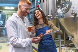 Man and woman tasting and checking craft beer quality, smiling and laughing together while