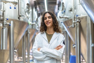 Woman wearing a lab coat standing confidently with crossed arms in a contemporary industrial