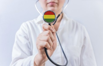 Female doctor holding stethoscope with Bolivia flag. National health system of Bolivia
