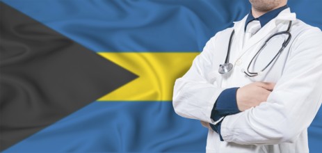Bahamas healthcare concept. Male doctor on Bahamas flag. Doctor with crossed arms on Bahamas flag
