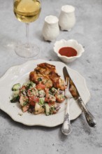 A well-prepared meal features grilled chicken, fresh salad with tomatoes and cucumbers, and a glass