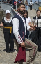 Man in traditional traditional costume performing movement, surrounded by people, folklore, Tatev,