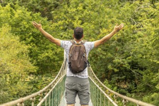 Backpacker opening his arms while enjoying the view from a hanging bridge over the sella river,