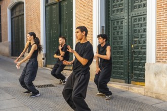 Group of young contemporary dancers moving in sync, expressing their art during a street