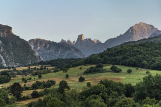 Golden hour sunlight illuminating the iconic naranjo de bulnes peak, towering over lush green