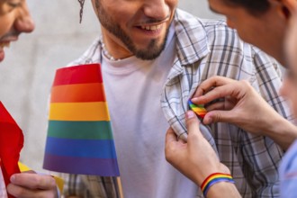 Happy man smiles as someone pins a rainbow flag badge to his plaid shirt, celebrating lgbtq pride,