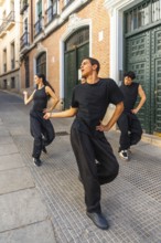Group of young modern dancers performing an energetic routine on a city street, expressing movement