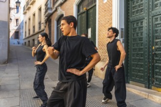 Young men and women in black clothing performing a synchronized dance routine on a cobblestone