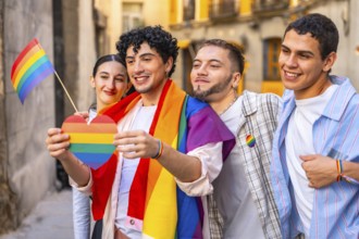 Young friends proudly displaying rainbow heart, flag and shawl at an outdoor pride celebration,