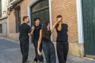 Young diverse friends dancing and laughing together on an urban street, holding hands and