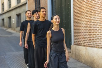 Young diverse dancers walking in line down a city street, smiling and energized while rehearsing