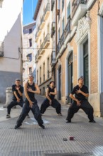 Group of four young dancers expressing movement and energy through a choreographed street