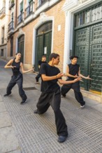 Group of young artists in black clothing performing a synchronized urban dance routine on a