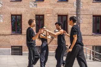 Group of diverse young performers wearing casual black clothing, happily dancing a contemporary