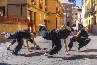 Group of young and energetic hip hop dancers moving in a synchronized street performance on a