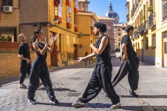 Dance troupe performing a contemporary routine on a cobblestone street, expressing passion and