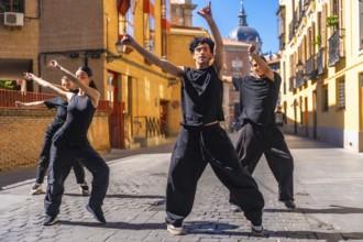 Group of four youth street dancers dressed in black performing contemporary choreography in a